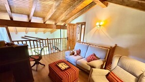 A cozy living room with a wooden ceiling, a sofa, a chair, and a small table. - Duplex ideal for families, swimming pool, fireplace and Wi-Fi (Sainte-Léocadie)