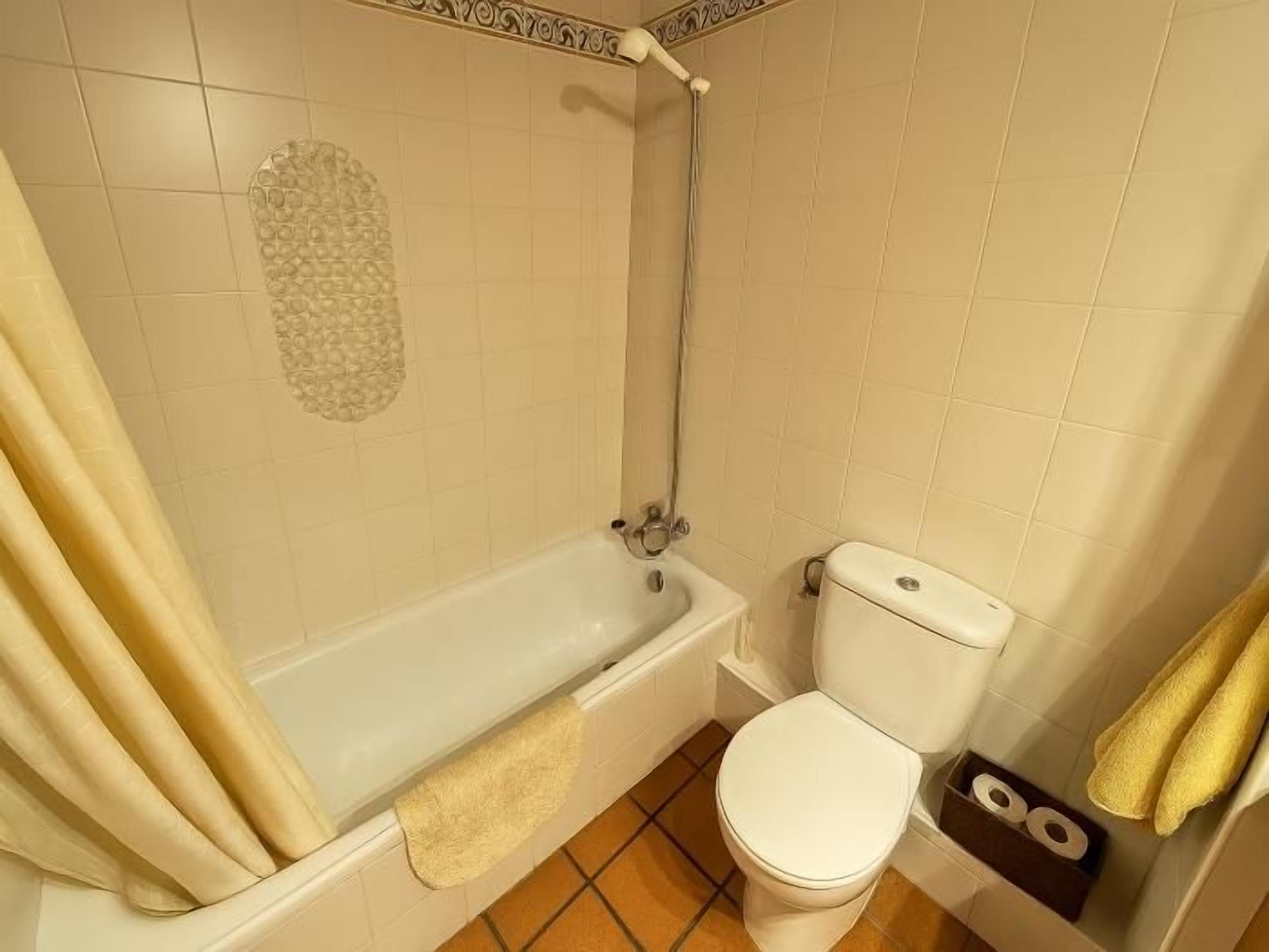 A bathroom with a bathtub, toilet, and shower.