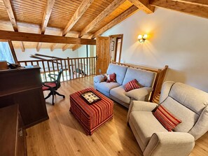 A spacious loft with wooden beams, a sofa, a chair, and a desk. - Duplex ideal for families, swimming pool, fireplace and Wi-Fi (Sainte-Léocadie)