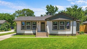 Ein Bungalow mit Veranda, Garage und einem gepflegten Rasen.