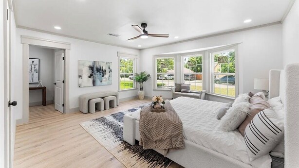 Ein Schlafzimmer mit Bett, Deckenventilator, Fenster und Tür.