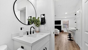 Un baño moderno con un espejo grande, tocador blanco y un inodoro.