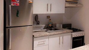 Cozinha moderna com armários brancos, geladeira de aço inoxidável, micro-ondas e fogão a gás.