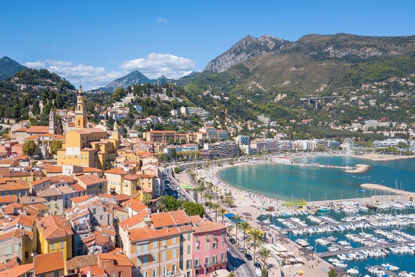 A coastal town with a marina, a prominent church, and a mountain backdrop.