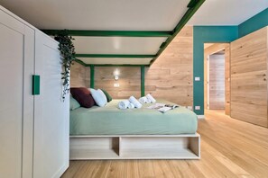 Ein modernes Schlafzimmer mit Bett, integrierten Stauraumöglichkeiten, einer Zimmerpflanze und Holzboden.