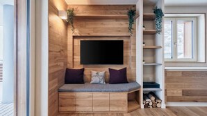 Un intérieur moderne avec un mur en bois, un téléviseur à écran plat, un banc avec des coussins et une plante.