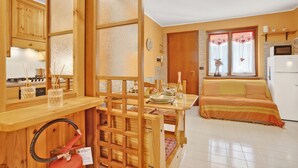 Eine kleine Küche mit Holzausstattung, einem Esstisch mit Stühlen, einem Sofa und einem Kühlschrank.