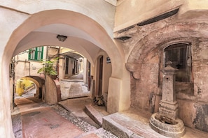 An arched corridor with a fountain, a staircase, and a view of a street with buildings. - EA Blue Marin Apartment with A/C, Sanremo, Italy (Sanremo)