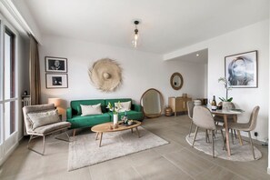 Una sala de estar moderna con un sofá verde, una mesa de centro de madera y un comedor con sillas y una mesa.