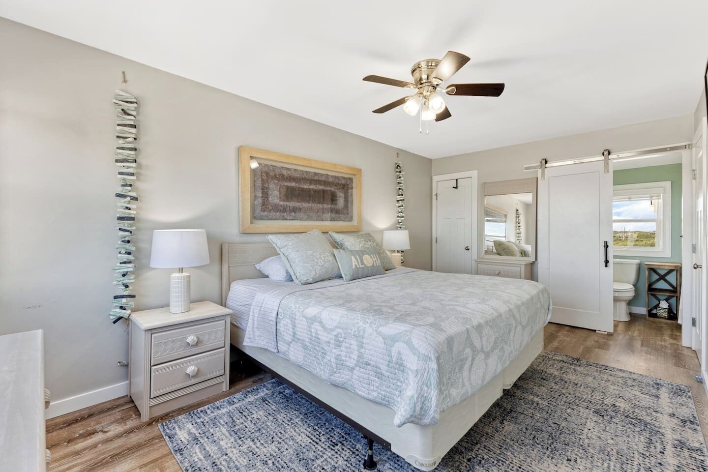 Une chambre à coucher avec un lit, des tables de chevet, un ventilateur de plafond, une porte et une vue sur l’extérieur.