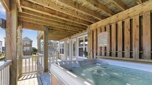 Ett trädäck med ett bubbelbad, en skylt med regler för spa-användning och utsikt över andra byggnader.