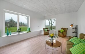 Ein großzügiger Wohnraum mit großen Fenstern, einem runden Couchtisch und einer Couch.