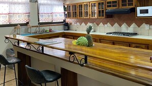 Une cuisine équipée d’un bar en bois, de tabourets de bar, d’un four à micro-ondes et d’une cuisinière à gaz.