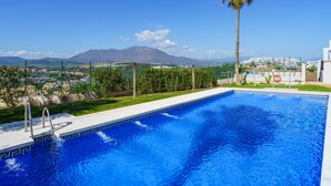 Ein Schwimmbad mit Blick auf einen Berg und ein weißes Gebäude im Hintergrund.