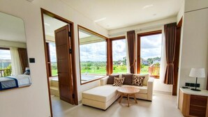A modern living room with a sofa, a round table, and a view of the countryside. - Mountain Sunshine Private Villa (Sukawati)