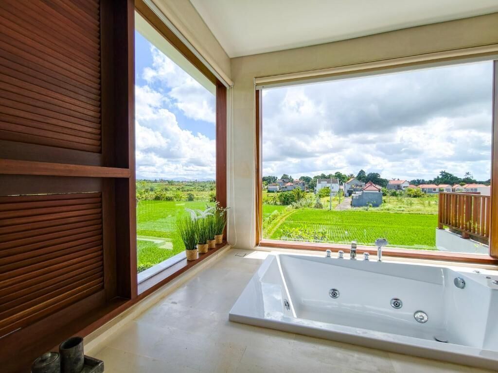 Un baño con un ventanal amplio, una bañera y vistas a un paisaje verde.