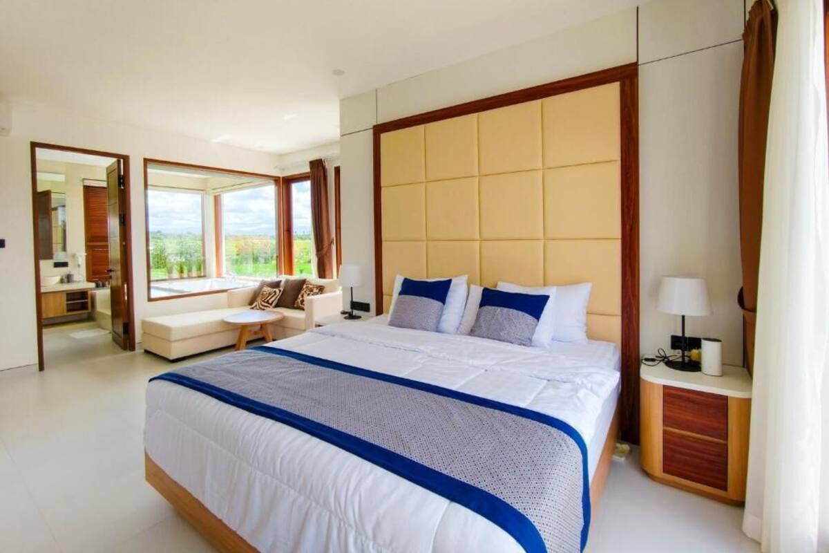 Camera d'albergo moderna con un letto grande, un'area salotto con vista e bagno separato.