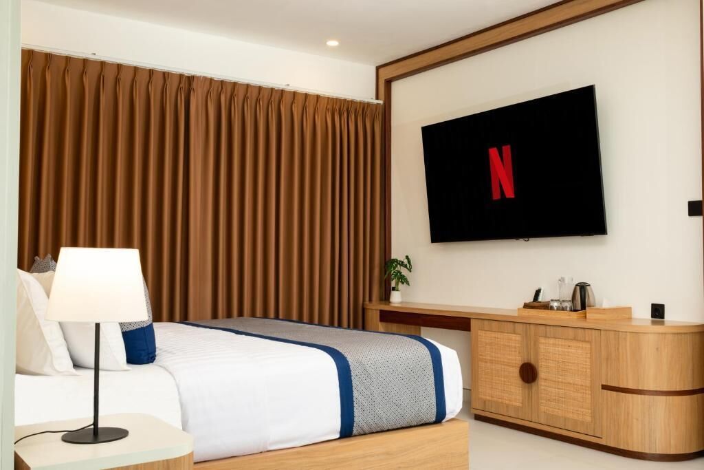 Une chambre d’hôtel équipée d’un lit, d’un téléviseur fixé au mur, d’un bureau et d’une armoire.