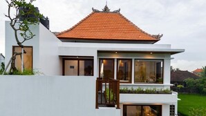 A modern two-story house with a tiled roof, large windows, and a balcony with plants. - Mountain Sunshine Private Villa (Sukawati)