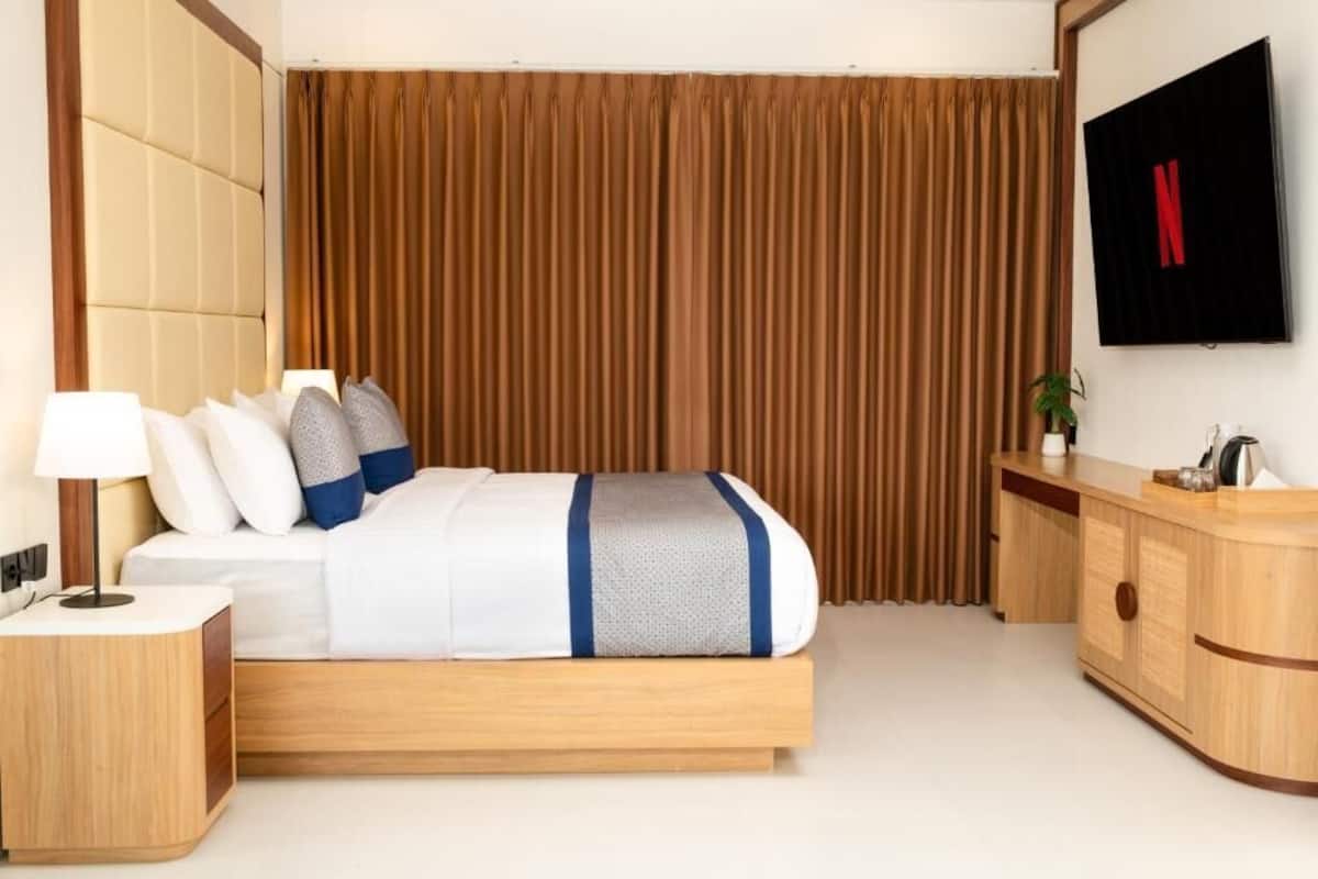Camera d'albergo con un letto, un comodino, una TV e un settimino in legno.
