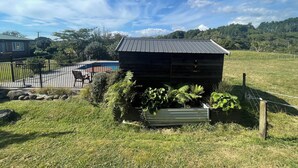 A rustic wooden cabin with a metal roof, surrounded by a fenced yard and a swimming pool.