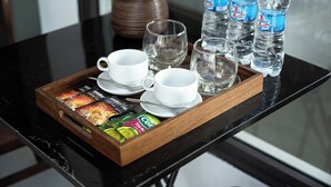 A tray with cups, a vase with flowers, and water bottles on a table. - Chu Homestay TamCoc (Nam Hoa Lu)