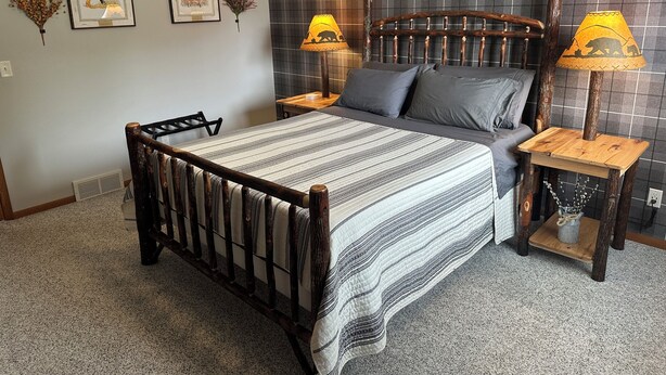 A bedroom with a wooden bed frame, two bedside tables with lamps, a headboard, and a wall with a grid pattern.