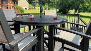 An outdoor patio with a round table, two chairs, and a red umbrella.
