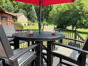 An outdoor patio with a round table, two chairs, and a red umbrella.