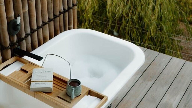 A spa bathtub with a wooden tray, a book, and a mug. - R&R Bus Retreat: Charles the white Bus (Wellington Mill)