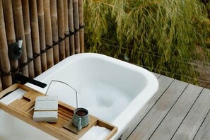 A spa bathtub with a wooden tray, a book, and a mug. - R&R Bus Retreat: Charles the white Bus (Wellington Mill)
