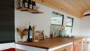 A kitchen with wooden cabinets, a wooden countertop, and a red appliance. - R&R Bus Retreat: Charles the white Bus (Wellington Mill)