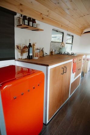 Una cucina con mobili in legno, un piano di lavoro in legno e un elettrodomestico rosso.