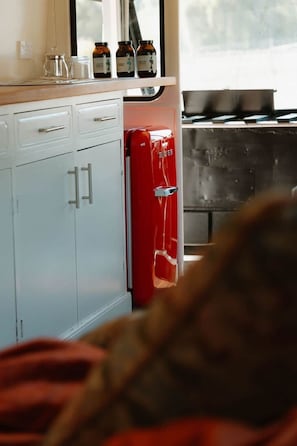 Una cocina con un armario blanco, un refrigerador rojo y una ventana con vistas.