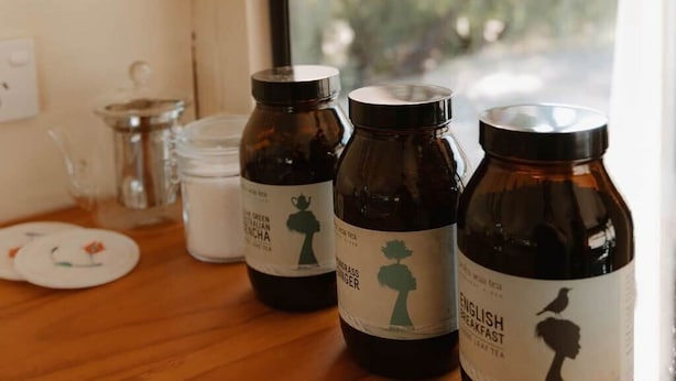 Trois bouteilles en verre, portant des étiquettes indiquant qu’elles contiennent du thé, sont posées sur une table en bois à l’intérieur d’un véhicule.