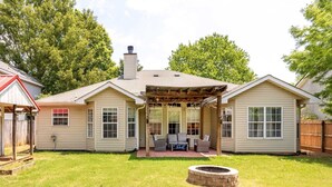 A two-story house with a covered porch, a fire pit in the yard, and a fenced backyard.