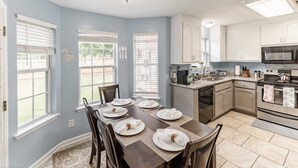 A kitchen with a dining table set for four, a microwave, stove, and cabinets.