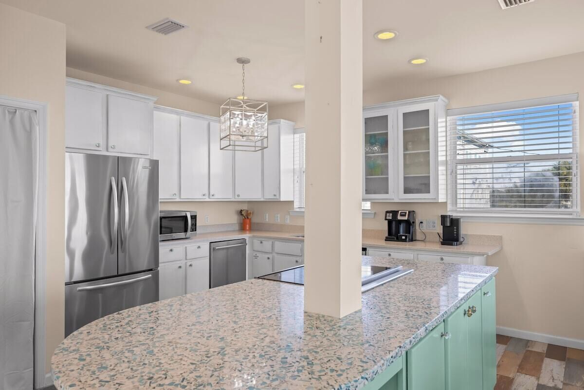 A kitchen with white cabinets, stainless steel appliances, a granite countertop, and a window with blinds.