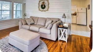 Uma sala de estar com sofá, apoio para os pés e uma mesinha lateral com cesta.