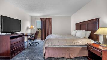 A hotel room with a bed, desk, TV, and a view through the window.