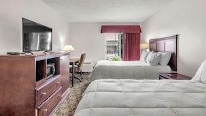 Una habitación de hotel con dos camas, un escritorio, un televisor y una ventana con cortinas.