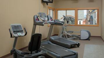 Un gimnasio con cintas de correr, bicicleta estática y máquina de remo.