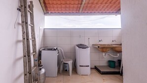 A small kitchen with a gas stove, a refrigerator, a washing machine, a sink, and a wooden ladder. - Apartamento Para 6 com Vaga e Churrasqueira (Para de Minas)