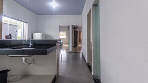 A modern kitchen with a large countertop, sink, and a refrigerator. - Apartamento Para 6 com Vaga e Churrasqueira (Para de Minas)