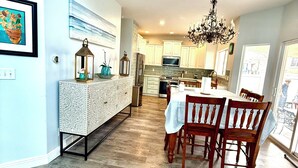 Une cuisine moderne avec un coin repas, un plancher en bois et un lustre.