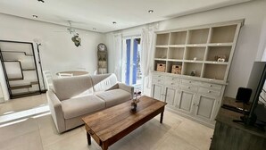 Un salón con un sofá, una mesa de centro de madera, un mueble para la televisión y una estantería empotrada.
