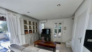 Una sala de estar con un sofá, televisor y estanterías empotradas.