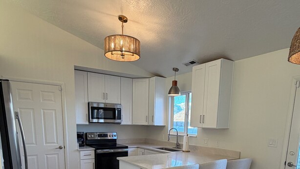 Una cocina moderna con armarios blancos, una isla central, taburetes de bar y una mesa de comedor.