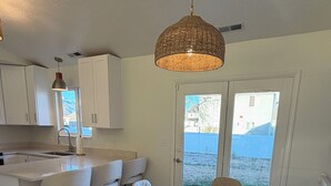 Una cocina moderna con armarios blancos, una mesa redonda con sillas y una lámpara colgante.