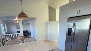 Una cocina moderna con lavavajillas empotrado, refrigerador de acero inoxidable y una lámpara colgante.